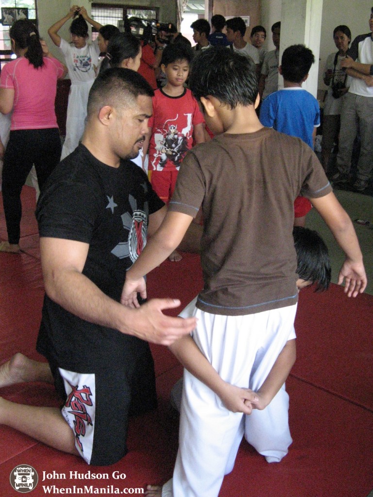 A hands-on Mark Munoz guiding one of the kids to execute a double leg takedown.