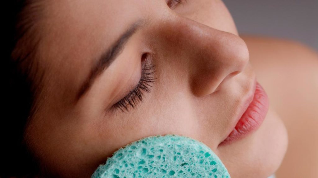 a person doing exfoliation on their face with a spong as that is how to remove dead skin from face