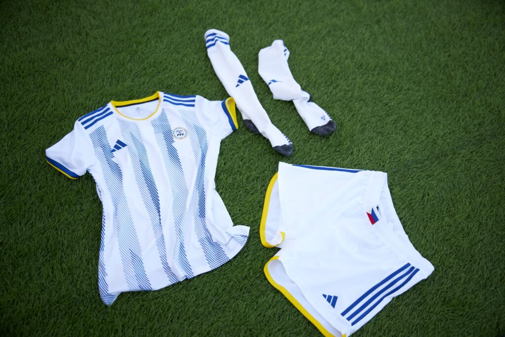 Ang Bagong Yugto. The away kit in white is adorned with three blue stripes and a collar decked in white and yellow
